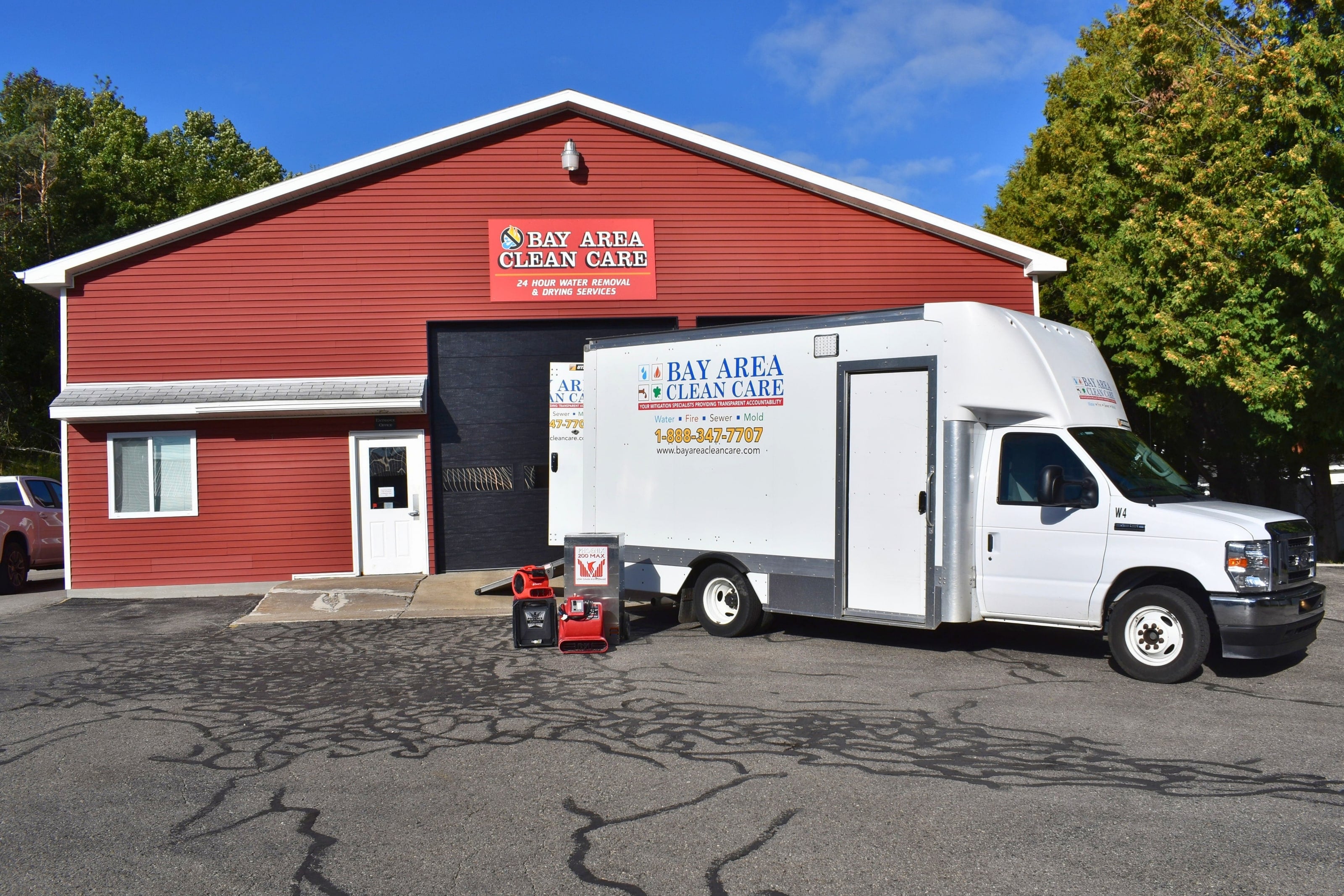 The Bay Area Clean Care restoration truck and a red air mover outside the shop in Petoskey