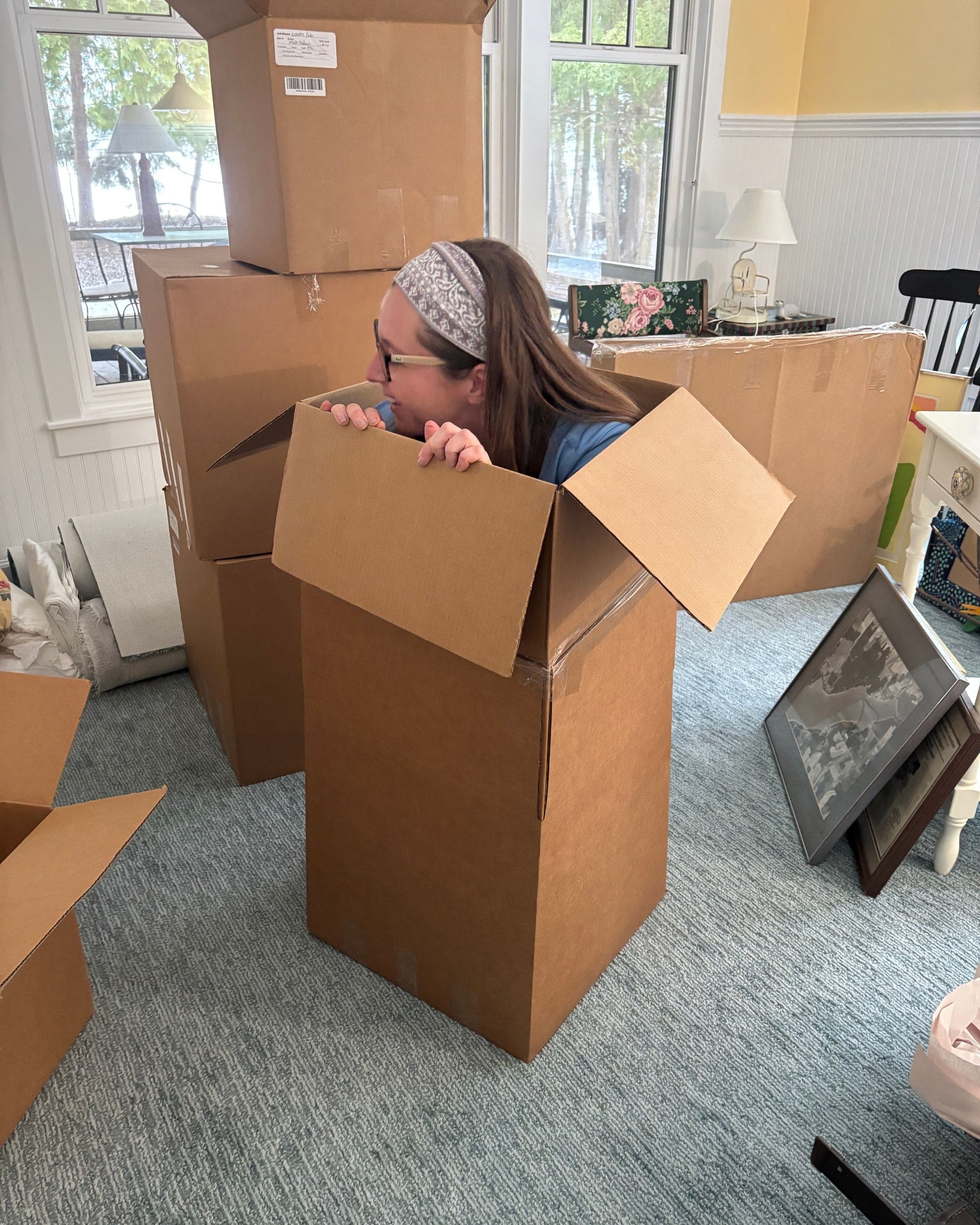 Rebecca from Bay Area Clean Care peeking out of a moving box during a pack-out, with packed boxes around her