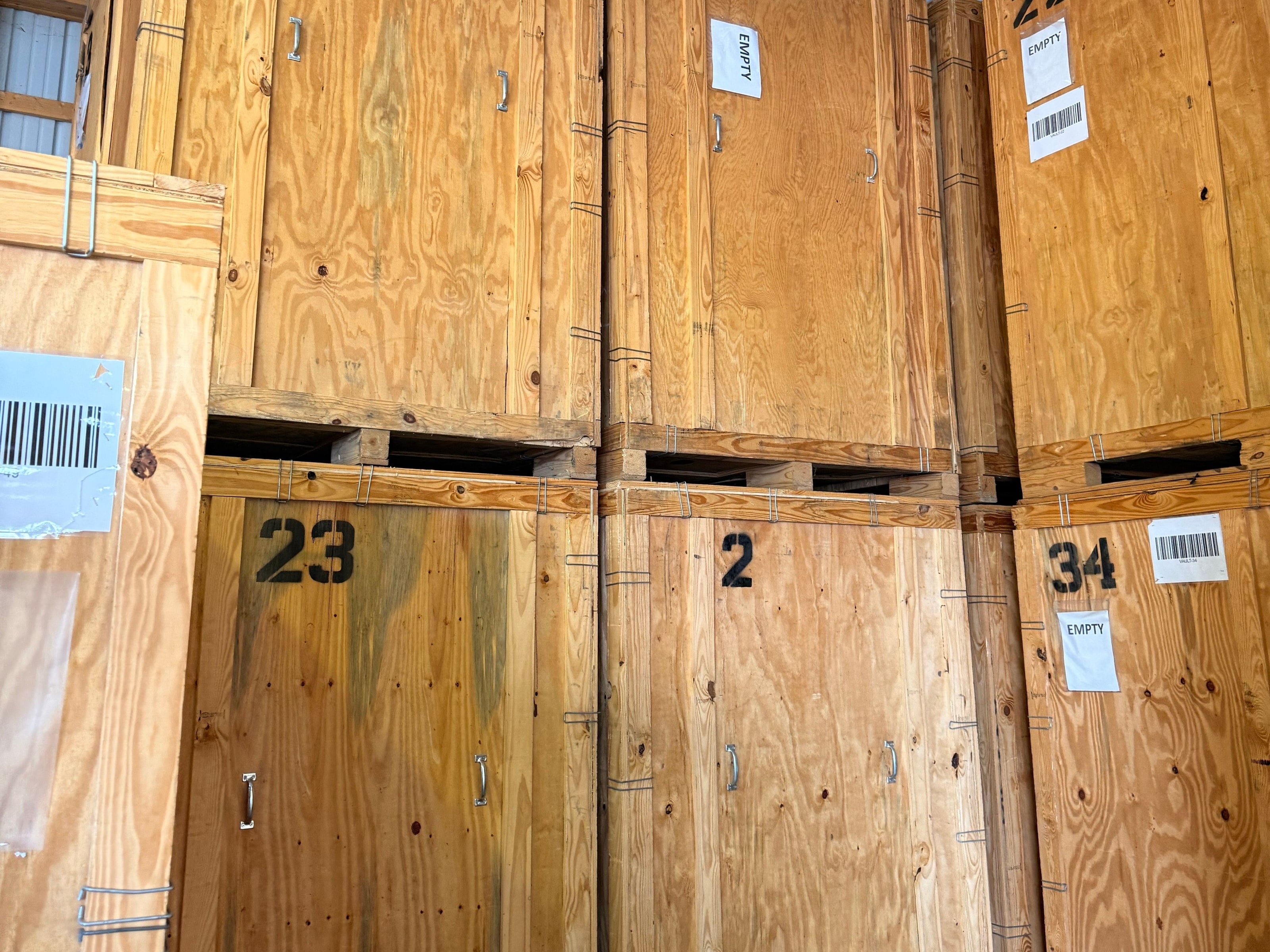 Numbered wooden storage vaults stacked two high in the Bay Area Clean Care warehouse, each with a barcode label