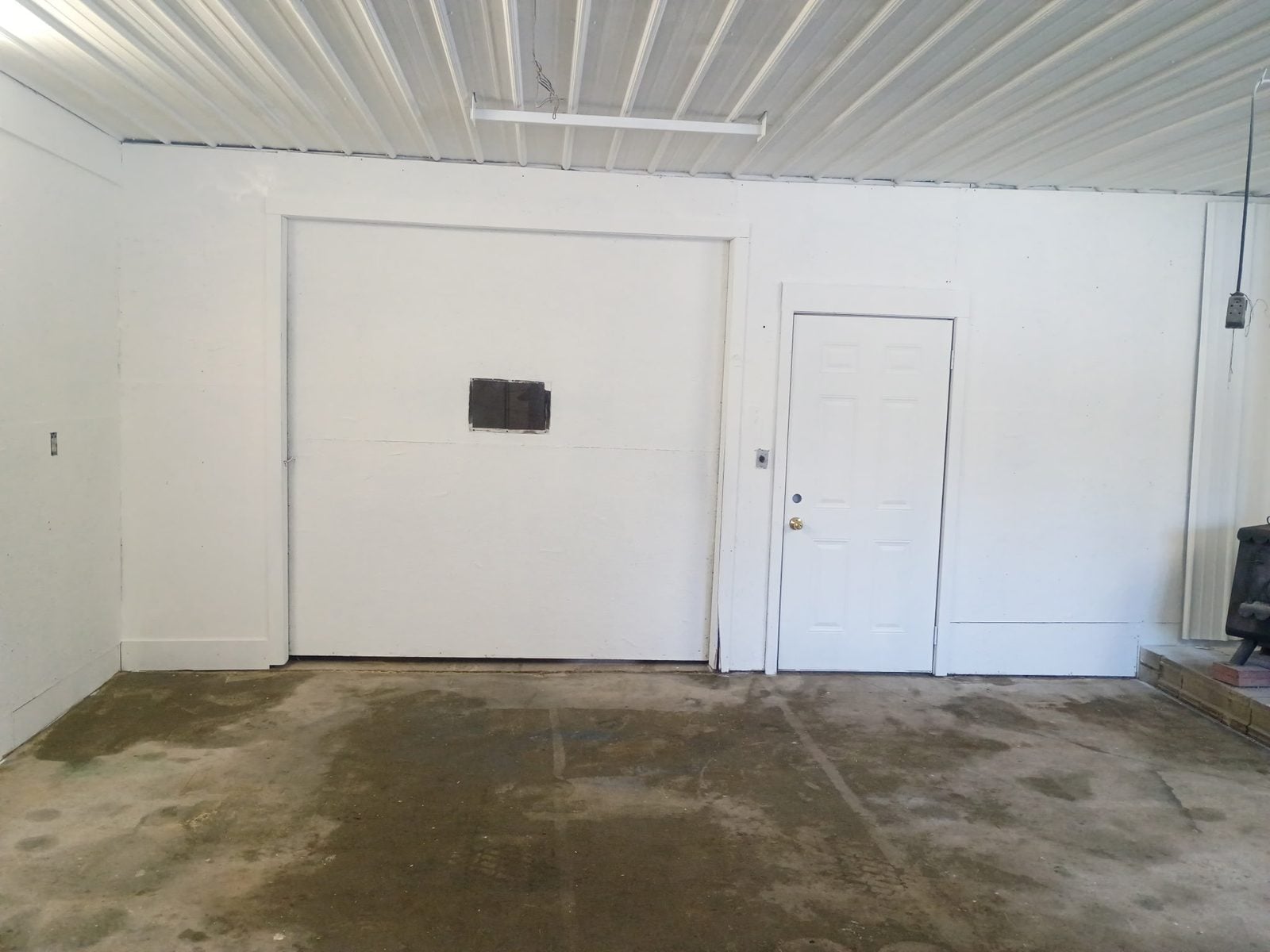 The same garage wall and door clean and white after fire and smoke restoration