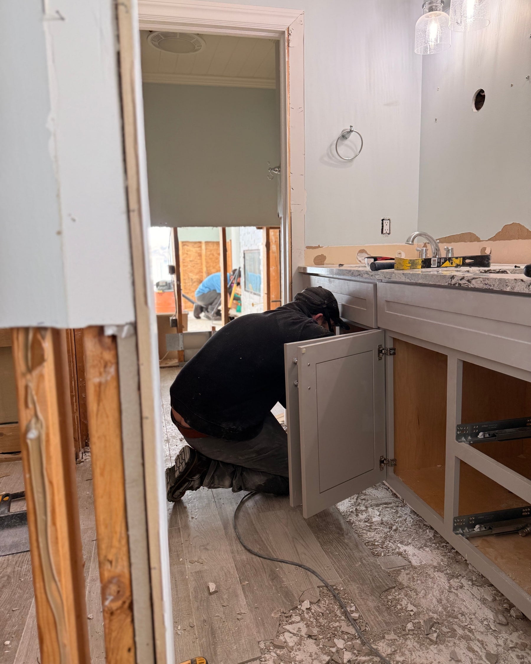 A technician working under a bathroom vanity during mold remediation, the walls opened to the studs